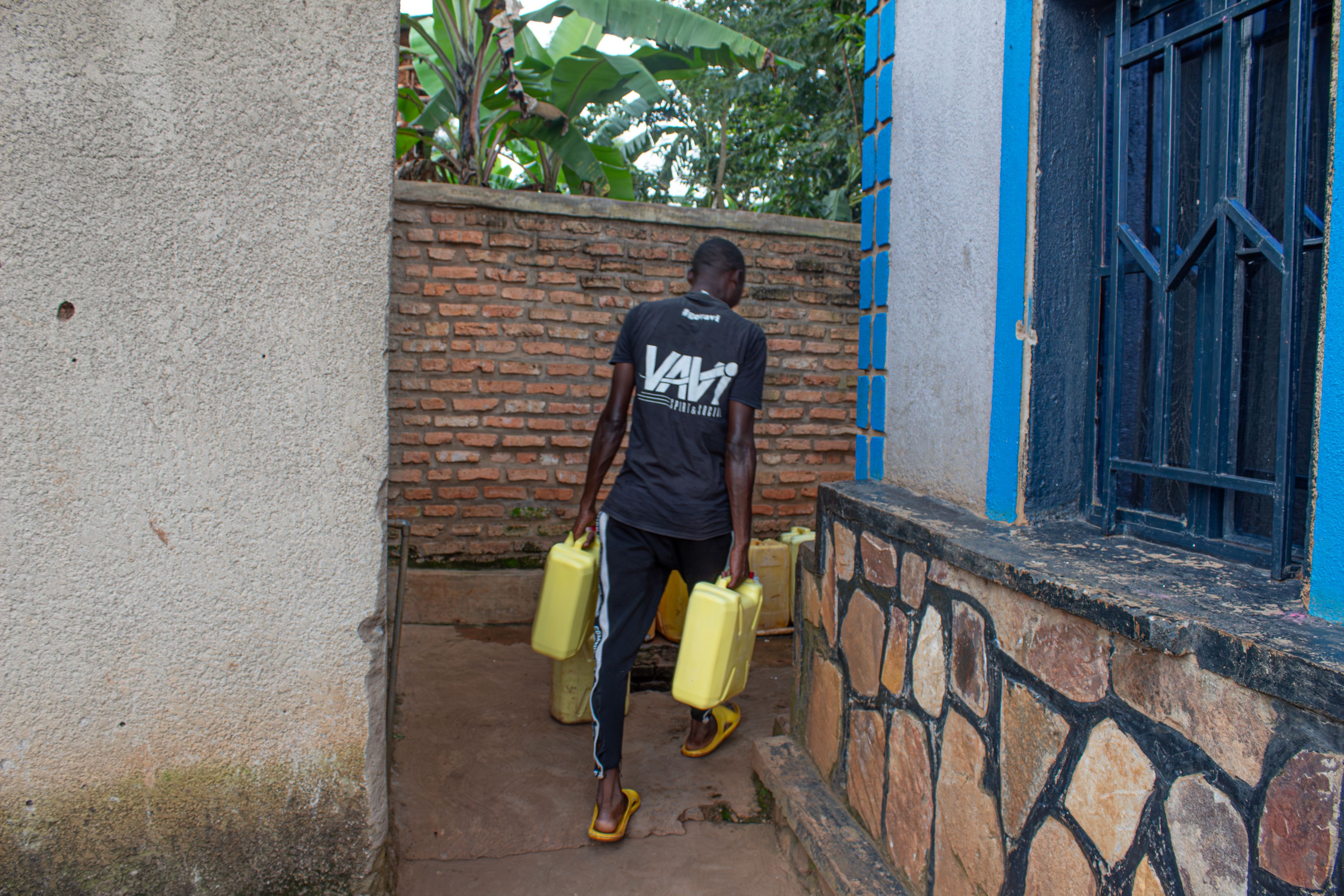 Celine’s employee Emmanuel transports milk in containers to a milk collection centre in Gishali