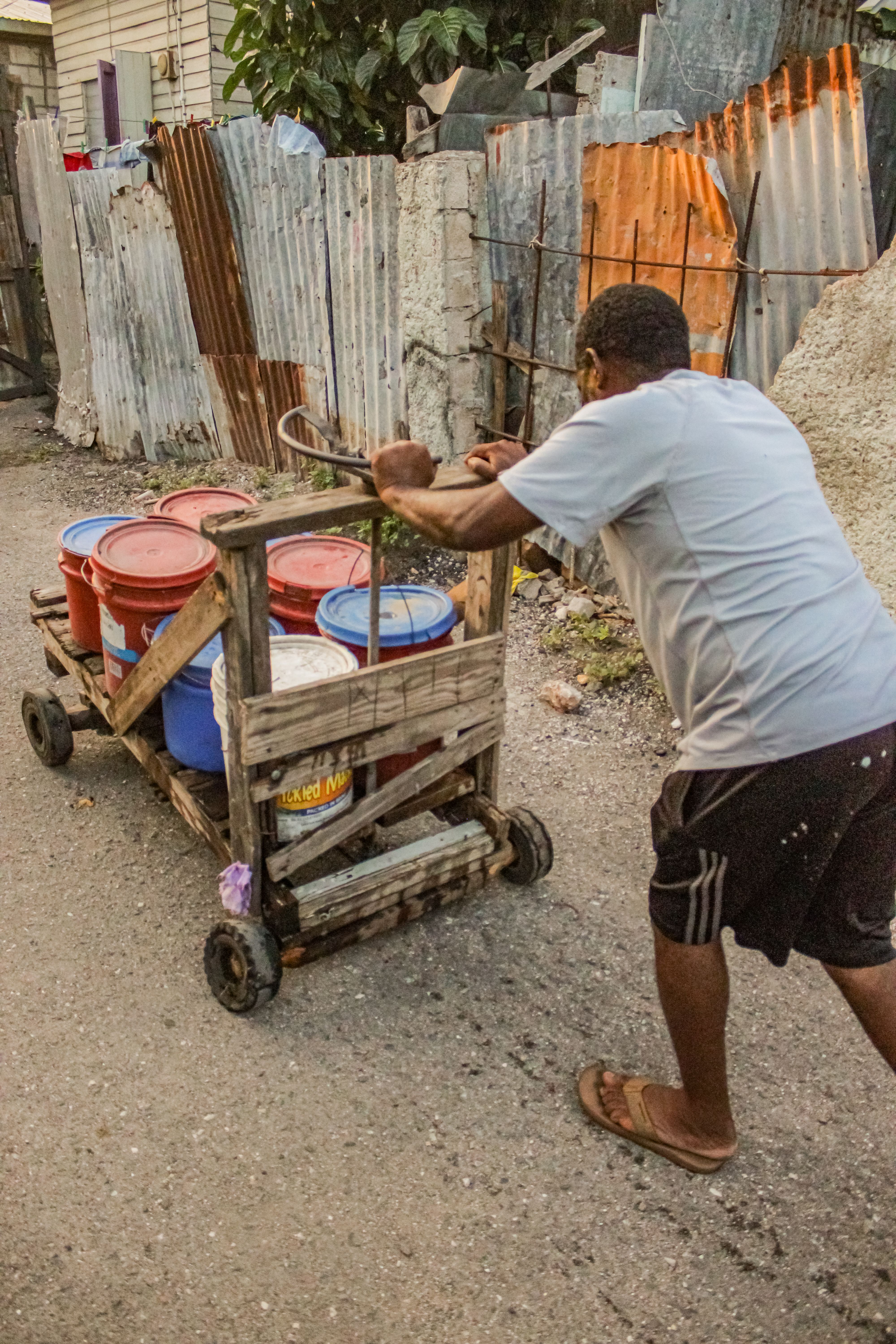 Raymond, another resident of Gordon Lane, is seen pushing his own cart, loaded with water-filled pails, by hand